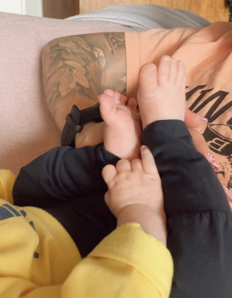 Vauvan jalat ja käsi joka kurkottaa niitä kohti
